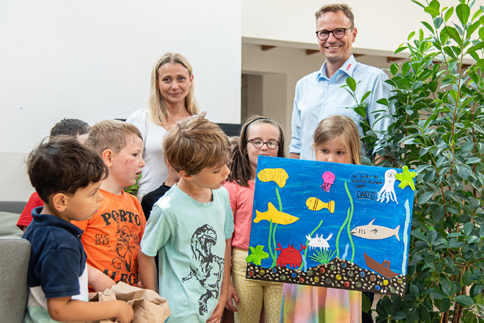 Einrichtungsleitung Katharina Billmann und die Kinder bedanken sich für die Spende bei Sera, hier vertreten durch Pressesprecher Oliver Helker, mit einem selbstgebastelten Aquariumbild. 