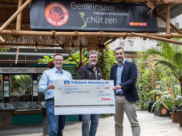 Oliver Helker (links) und Simon Gierlings (beide sera) übergeben den Spendencheck an Prof. Dr. Thomas Ziegler im Kölner Zoo (Bildmitte). 
